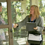 US Census taker greeting resident at the front door with a handshake.