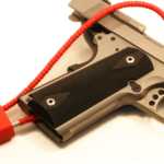 Close-up cropped view of a red cable lock on a semi-automatic pistol.