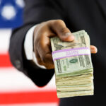 Politician: Offering Stack Of US Money To Camera