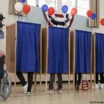 People voting in polling place; one voter in a wheelchair voting at a separate machine