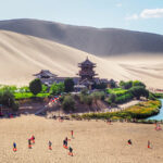 crescent-shaped of oasis lake and beautiful pagoda in Gobi desert,