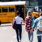 group of teen students walking to school bus