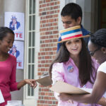 A female high school student campaigning for voter registration outside a high school building,