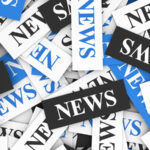 News concept background with a multitude of signs and text on scattered paper.